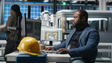 Afrikalı Amerikalı denetçi güneş paneli makinelerini kontrol ediyor ve yenilenebilir enerji üretimi ve üretim hattında hayati bir rol oynayan bir kontrol listesini gözden geçiriyor. Güneş teknolojisi altyapısı. Kamera A.