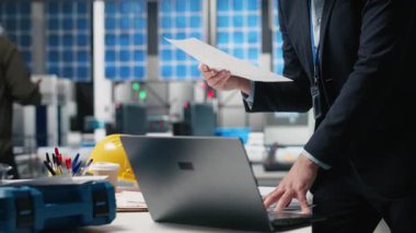 Sanayi işyerindeki güneş enerjisi sistemlerini denetleyen idari danışman, sürdürülebilir enerji gelişimi için stratejik planlamayı vurguluyor. Temiz enerji üretim hattında yenilik. Kamera A.