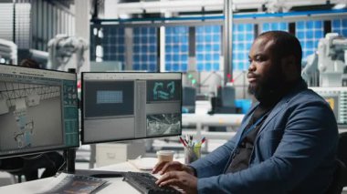 Afrika kökenli Amerikalı usta mühendis bir güneş teknolojisi fabrikasında yeşil enerji hedeflerine ulaşmak için fabrika faaliyetlerini inceliyor. Uzman, üretim verimliliği için tablet kullanır. Kamera B.