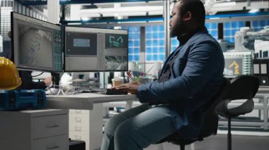 Siyahi endüstriyel uzman, güneş paneli fabrikası kurarak, temiz sürdürülebilir enerji üzerinde çalışarak, bilgisayar üzerindeki montaj sürecini inceliyor. Üretim akışı için mühendislik yeniliği. Kamera B.