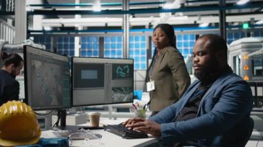 Afrika kökenli Amerikalı usta mühendisler güneş enerjisi fabrikasındaki fotovoltaik aktiviteleri inceliyor, üretim süreci için veri ve kontrol listelerini gözden geçiriyorlar. Çevre dostu yenilenebilir enerji. Kamera B.