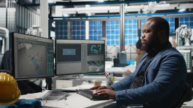 Afrikalı Amerikalı denetçi güneş paneli makinelerini kontrol ediyor ve yenilenebilir enerji üretimi ve üretim hattında hayati bir rol oynayan bir kontrol listesini gözden geçiriyor. Güneş teknolojisi altyapısı. Kamera B.