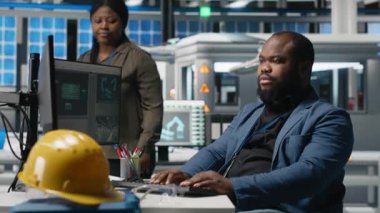 İnceleme sırasında güneş paneli üretim sistemlerini inceleyen, mühendislik doğruluğu ve kalite kontrolü sağlayan Afrika kökenli Amerikalı uzmanlardan oluşan bir ekip. Yüksek teknoloji endüstriyel fabrika. Kamera A.