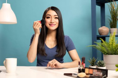 Dost canlısı güzellik uzmanı, çevrimiçi makyaj dersi veriyor ve fırça kullanmanın farklı yollarını gösteriyor. Stüdyosundaki Asyalı içerik yaratıcısı kozmetik aletler hakkında yaşıyor..