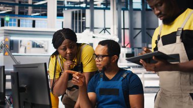 Fotovoltaik fabrikasındaki teknisyenler güneş panelleri montaj hatlarını inceliyor, sanayi yönergelerini okuyor ve sorunsuz üretim sağlıyorlar. Siyah takım güneş pili aktivitesini optimize ediyor. Kamera B.