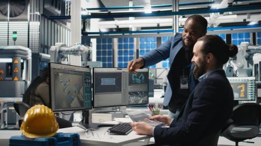 Fabrikadaki iş arkadaşları güneş enerjisi üretim hattını denetleyerek fotovoltaik geliştirme sürecinde takım çalışması gösteriyor. Yenilenebilir enerji altyapı sistemleri. Kamera A.