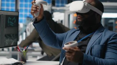 Fotovoltaik üretim tesisi analisti sistem performansını ve güneş panelleri üretim hattını izlemek için VR teçhizatıyla çalışıyor. Afrikalı Amerikalı uzman sanal gerçekliği kullanıyor. Kamera A.