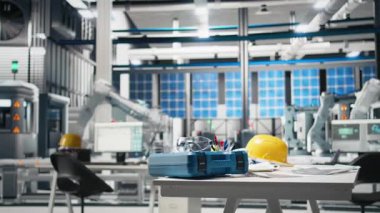 Robotları iş başında gösteren yüksek teknoloji imalat ortamı, fotovoltaik sistem izleme ve masada gerekli güvenlik ekipmanları. Modern yenilenebilir enerji üretim hattı.