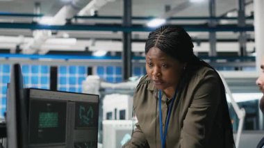 Fotovoltaik üretim hattının ayrıntılarını paylaşan çok ırklı uzmanlardan oluşan bir ekip, yenilenebilir enerji için güneş panelleri üretilmesini güvence altına almak için ölçümleri inceliyor. Dayanıklılık. Kamera A.