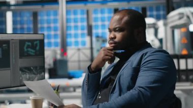Master engineer reviewing production line metrics on papers, managing factory activity in a solar panel facility to ensure effective quality control to renewable energy tech. Camera A.