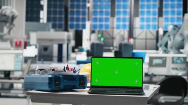 Boş fotovoltaik masasındaki bir dizüstü bilgisayardaki yeşil ekran, güneş panelleri imalat tesisinde enerji arzını optimize etmek için kullanılıyor. Yüksek teknoloji mühendisliği endüstrisi.