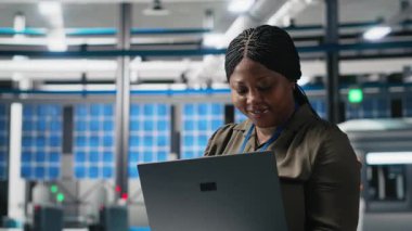 Afrika kökenli Amerikalı kadın, endüstriyel işlemleri gösteren alternatif enerji üretiminde kullanılan güneş panelleri fabrikasında sistem kontrollerini kontrol ediyor. Mühendislik. Kamera A.