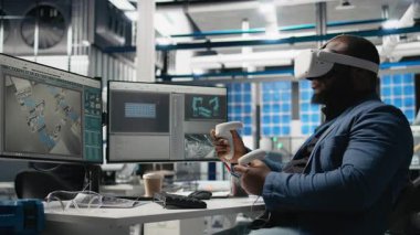 Siyah fotovoltaik fabrikası uzmanı, güneş panellerini yerleştirmek için robotik kollarla çalışan dijital güneş pillerini monte etmek için VR gözlükleri kullanıyor. Mühendis sanal gerçeklikte makineler kullanır. Kamera B.