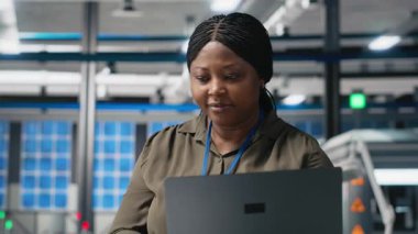 Afrika kökenli Amerikalı kadın uzman güneş panelleri üretim hattını inceliyor, bir fotovoltaik fabrikasında kalite kontrolü yapıyor. Güneş enerjisi yaratmak için veri raporları ve içgörü analiz ediliyor. Kamera A.