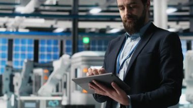 Endüstriyel erkek giysi uzmanı güneş enerjisi ekipmanlarını denetliyor, kalite kontrol ve üretim hattında verimlilik gösteriyor. Güneş panelleri üretiminde çalışıyorum. Kamera A.