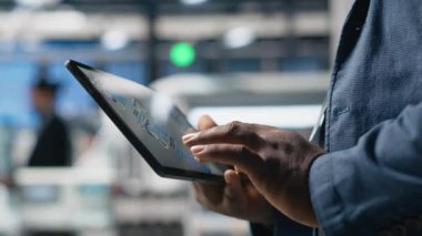 Sanayi uzmanı tabletteki dijital üretim sistemlerini fabrikadaki güneş enerjisi üretim hattını kontrol ediyor. Siyahi uzmanlar güneş santralinde endüstri mühendisliği gösteriyor. Kapatın. Kamera A.