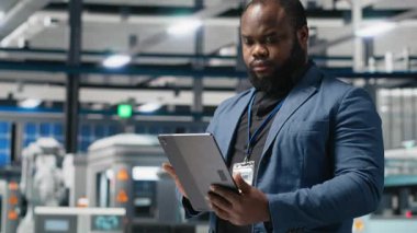 Siyah endüstri uzmanı yenilenebilir enerji başarısını sürdürmek için yenilik ve verimlilik sağlayan bir güneş teknolojisi tesisinde üretim verilerini inceliyor. Çevre dostu sürdürülebilir çözümler. Kamera A.