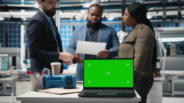 Danışmanlar ve fabrika analistleri güneş paneli tesisinde her detayı temiz enerji verimliliği ve güneş enerjisi yeniliğiyle aynı hizaya getirmek için bir kopya ekran üzerinde çalışıyorlar. Kamera B.