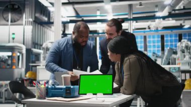 Çok ırklı enerji danışmanları kroma anahtarının yanındaki üretim hattını koordine ederek, yüksek teknolojili bir güneş enerjisi tesisinde kalite kontrol tedbirleri alıyorlar. Kurumsal gözetim ve infaz. Kamera B.