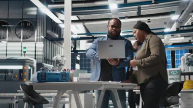 Afrika kökenli Amerikalı endüstriyel çalışanlar güneş panelleri için üretim hattı üzerinde takım çalışması yapıyorlar, teknik içgörü ve takım çalışmasını birleştirerek temiz enerji altyapısını ileriye taşıyorlar. Kamera B.