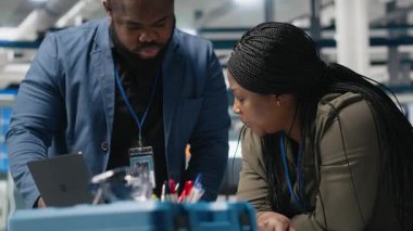 Afrikalı Amerikalı teknik uzmanlardan oluşan bir ekip, yenilenebilir enerji ve endüstriyel operasyonlarda gelecekteki gelişmeleri planlamak için yüksek teknoloji santralinde brifing üzerinde çalışıyor. Üretim süreci. Kamera A.