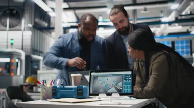Siyah mühendislik uzmanları güneş enerjisi üretim fabrikasındaki operasyonel iş akışlarını inceliyor. Mühendisler alternatif enerji üretim hattı ve geliştirme ile takım çalışmasını entegre ediyorlar. Kamera B.