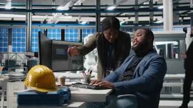 Siyahi mühendisler teknisyenleri bir güneş paneli fabrikasında fikirlerini paylaşıyor, projeleri gözden geçiriyor ve yenilenebilir enerji üretimini ve sürdürülebilir yeniliği geliştirmek için fikirlerini paylaşıyor. Kamera B.