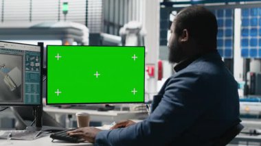 PC 'nin yanındaki montaj hattını inceleyen erkek teknoloji uzmanı, yeşil enerjinin etkin kalite kontrolü ve taahhütünü sağlamak için güneş enerjisi santralindeki fabrika operasyonlarını yönetiyor. Kamera A.