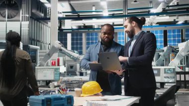 Çok ırklı iş ortakları ve mühendisler, sürdürülebilir enerji ve sanayi operasyonlarında gelecekteki gelişmeleri planlayan bir güneş teknolojisi üretim tesisinde bir tartışma için bir araya geldiler. Kamera B.