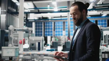 Genel müdür, temiz enerji endüstrisi ekipmanlarıyla modern üretim hattını sembolize eden bir güneş paneli imalat tesisinde teftiş yapıyor. Sürdürülebilir çözümler. Kamera B.