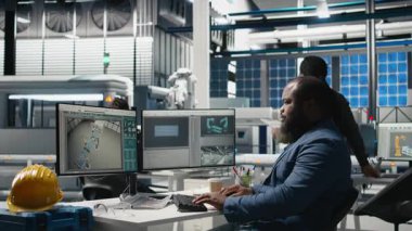 Bir güneş paneli fabrikasındaki performans verilerini kontrol eden endüstriyel operasyonlar uzmanı, işyeri verimliliğine olan bağlılığını gösteriyor ve yeşil enerji imalatı ve mühendisliği üzerinde çalışıyor. Kamera B.