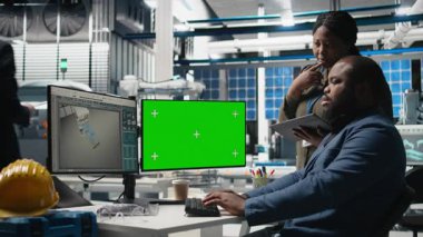 Güneş enerjisi çeşitliliği ekibi yeşil ekranın yanındaki bilgisayarı inceliyor, üretim sırasında hatalar buluyor ve temiz enerji operasyonlarının optimize edilmesine yardım ediyor. Fotovoltaik. Kamera B.