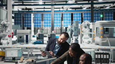 Siyah endüstri mühendisleri üretim denetimi sırasında güneş paneli sistemleri üzerinde birlikte çalışarak mühendislik doğruluğu, kalite kontrolü ve fabrika işletim verimliliğini sağlıyorlar. Kamera B.