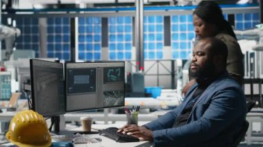 Bir güneş paneli enerji santralinde işbirliği yapan çok ırklı uzmanlardan oluşan bir ekip, temiz enerji üretimi ve sürdürülebilirliği sağlamak için planlar ve üretim hattı metriklerini gözden geçiriyor. Kamera A.