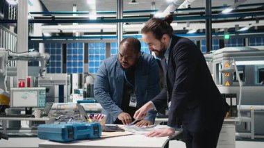 Çok ırklı mühendisler, güneş panelleri için üretim hattı üzerinde takım çalışması yapan endüstriyel iş arkadaşları, temiz enerji altyapısını ilerletmek için teknik içgörü ve takım çalışmasını birleştiriyorlar. Kamera B.