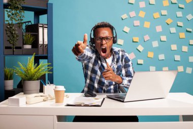 Pozitif sonucu kutlayan neşeli girişimci, kameraya onay jestleri yaparak coşkusunu dile getiriyor. Genç bir erkek çalışan masada oturuyor ve zam aldıktan sonra heyecanla bağırıyor..