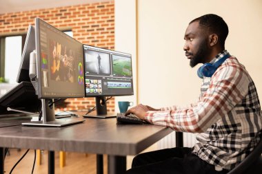 Afrikalı Amerikalı dijital film yapımcısı multimedya görüntülerine renk derecelendirme ve yaratıcı kurgu uyguluyor. Siyah erkek içerik oluşturucu, video montajını profesyonel post prodüksiyon yazılımıyla inceliyor.