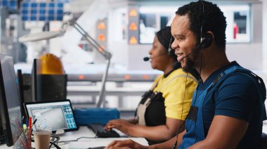 Mühendis, güneş paneli fabrikasındaki kulaklıkla teknik destek sağlıyor, operatör müşterilere güneş enerjisi teçhizatı sorunlarında yardımcı oluyor. Yardım hattında etkili bir iletişim sağlanıyor. Kamera A.
