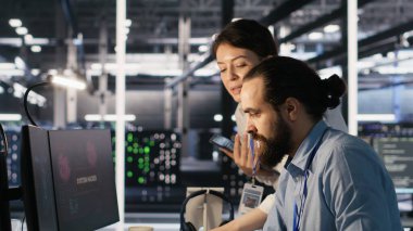 Veri merkezindeki kaygılı teknisyenler fidye yazılımının neden olduğu kilitlenmeye tepki veriyorlar. Güvenlik ihlallerini değerlendiren ve hasarı kontrol altına almak için çabalayan bilişim uzmanları, kamera A