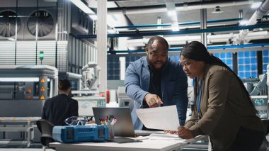 Afrika kökenli Amerikalı endüstriyel çalışanlar güneş panelleri için üretim hattı üzerinde takım çalışması yapıyorlar, teknik içgörü ve takım çalışmasını birleştirerek temiz enerji altyapısını ileriye taşıyorlar. Kamera A.