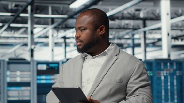 Endüstriyel veri merkezinde bilişim uzmanı altyapı performansını analiz ederek, devre dışı kalma ve ekipman arızalarını en aza indiriyor. Sunucu çiftlik işçisi iş yapıyor, otomatikleştirilmiş anomali saptama, kamera B