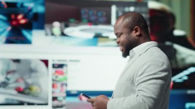 Adam dijital video duvarının önünde akıllı telefondan sosyal medyada geziniyor. Arkasında yüzen baş parmaklı ve kalp simgeleri olan bir telefon kullanan, interaktif bağlantının altını çizen, kamera A