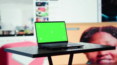 Sosyal medya beslemesinde çevrimiçi videoları gösteren video duvarının önündeki yeşil ekran laptop. İnternet bağlantısını ve multimedya eğlencesini gösteren maket defteri ve dijital arayüz