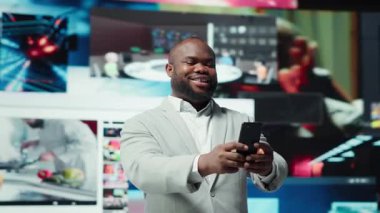 Joyous man using phone, receiving personalized video recommendations delivered instantly. Upbeat user using smartphone, enjoying digital era enabling unlimited streaming opportunities