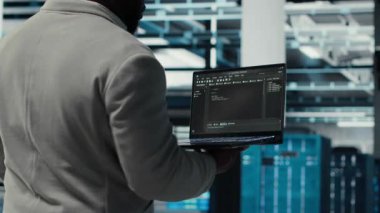 Veri merkezinde yürüyen neşeli bir yönetici sistem dengesi için teçhizatı kontrol ediyor. Jolly IT profesyonel sunucu merkezi, rafları yapılandırma, performansı optimize etme, kamera B