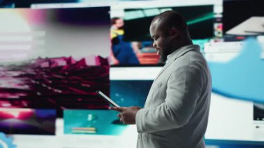 Gülümseyen kişi tablet kullanıyor, çevrimiçi video içeriği ile boş zamanların tadını çıkarıyor. Neşeli bir adam kolaj kolajı ve kamera A ile dolu dijital arkaplan önündeki sosyal medya uygulamasına göz atıyor.