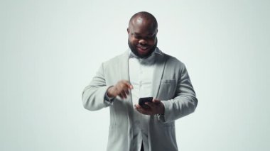 Gülümseyen adam bir tuşa basarak binlerce videoya erişebiliyor. Neşeli Afro-Amerikan erkeği boş zamanlarında akıllı telefondaki favori online videolara göz gezdirmeyi sever. Kamera A