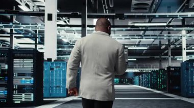 Sistem istikrarı için yazılım güncellemelerini yönetmek için dizüstü bilgisayar kullanan veri merkezi teknisyeni. Afro-Amerikan sunucu odası bilişim uzmanı performansı optimize ediyor, altyapıyı yapılandırıyor, kamera A