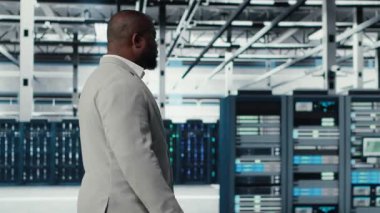 Sistem yöneticisi veri merkezinde sorguları kontrol eden platformlarla yürüyor, yedekleme yapıyor. Dijital hizmetlere ev sahipliği yapan, müşteri platformlarına güç veren sunucu çiftliği yönetimi, kamera B