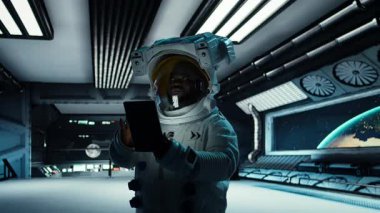 Astronot araştırmacı, araştırma yapmak için tablet kullanıyor. Uzay gemisinde kozmonot teçhizatı giyen bilim adamları uçuş sırasında yaşam destek sistemlerini izliyorlar.